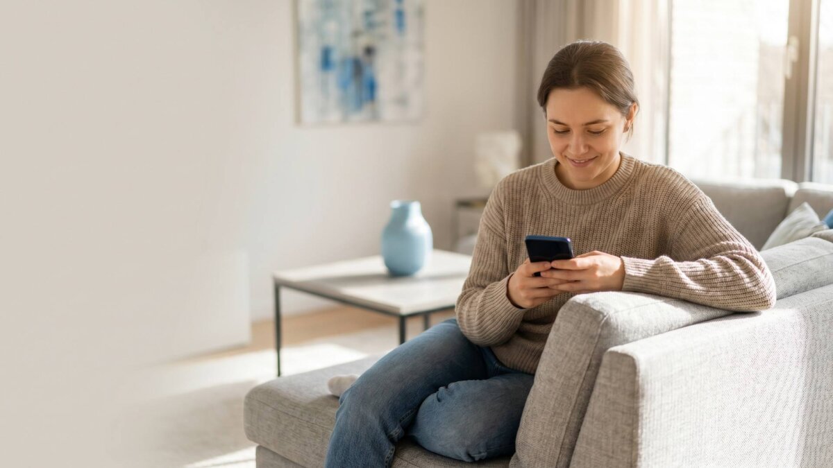 Person bucht auf dem Sofa per Smartphone eine Reinigung